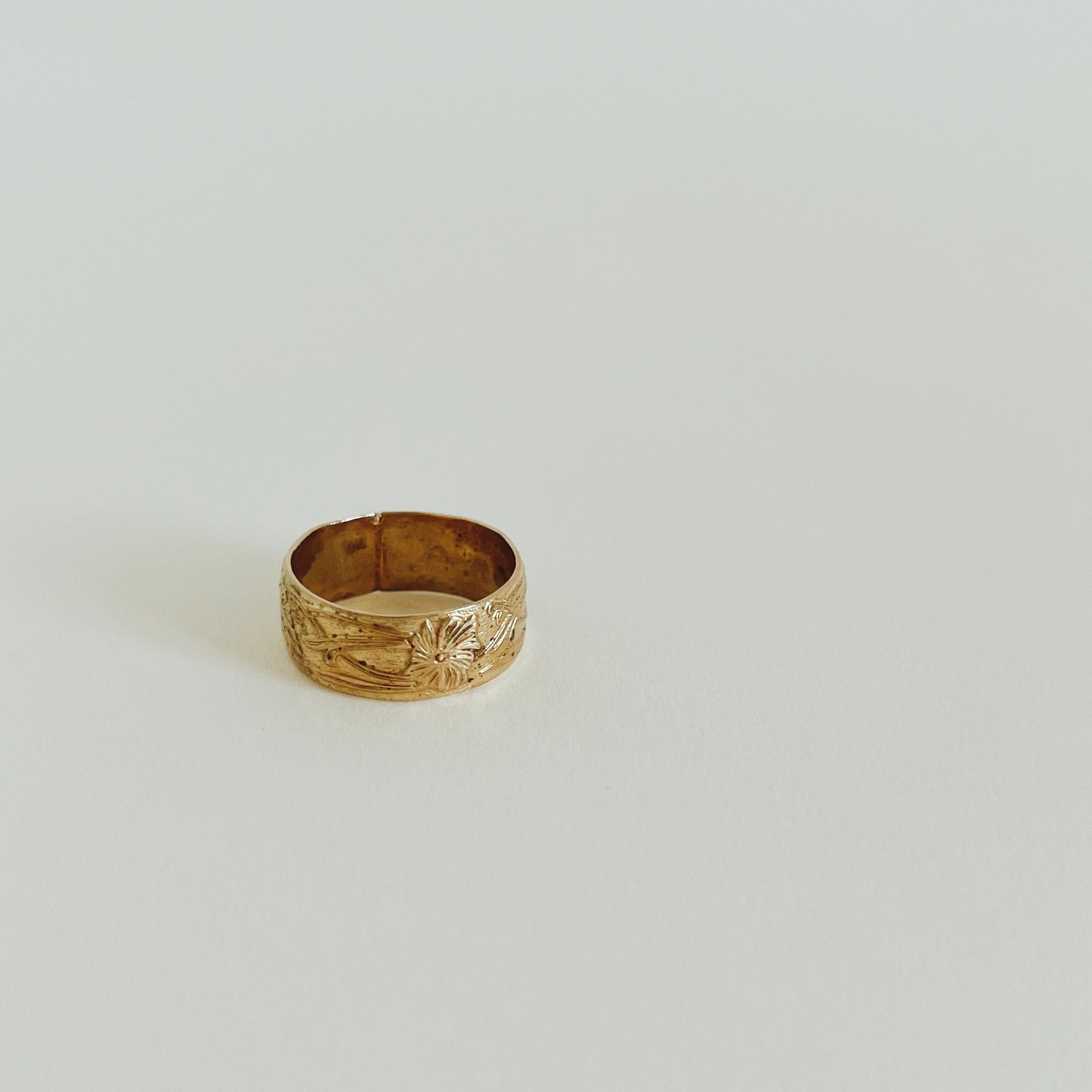 think gold ring with engraved flowers on white background. 
