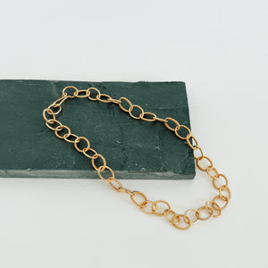 Gold chunky chain necklace on green rock.