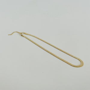 Gold snake chain necklace on white background.