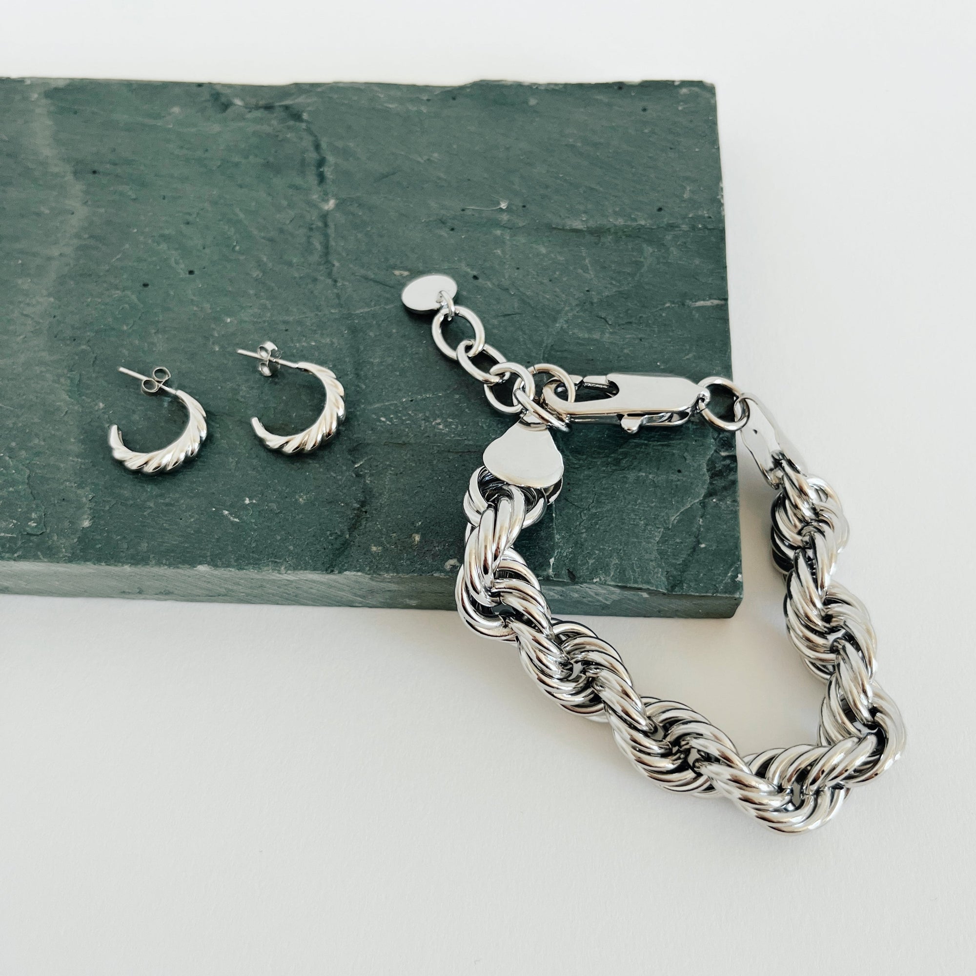silver kate rope bracelet with silver hoop earrings on green rock